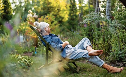 Mature woman relaxing in deckchair in her garden