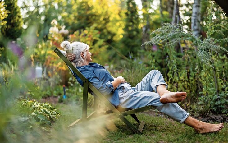 Mature woman relaxing in deckchair in her garden