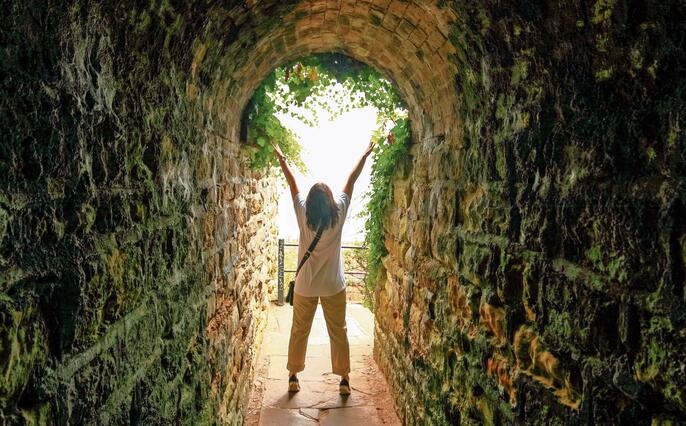 Silhouette of a lady with raised hands at the end of a tunnel