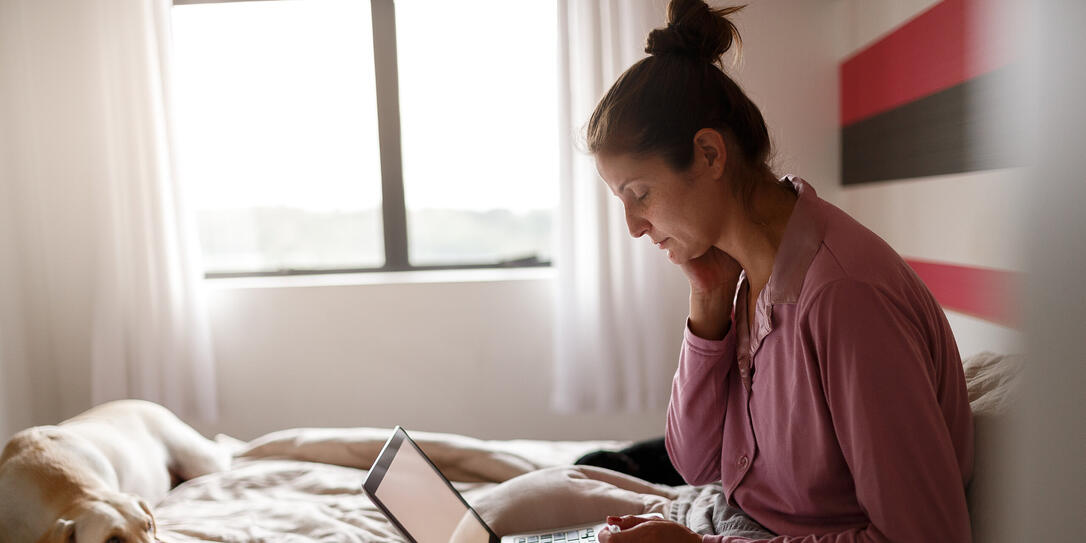 Sick woman on bed video chatting with doctor on laptop Sick woman on bed video chatting with doctor on laptop