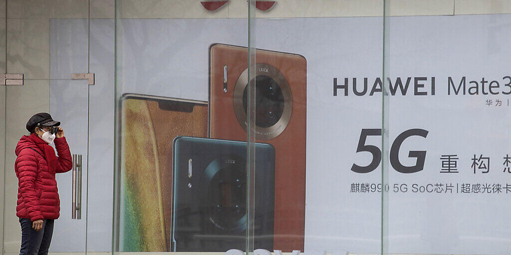 ARCHIV - Eine Frau mit Mundschutz steht vor einer Werbung für Smartphones von Huawei. China hat zwei festgehaltene Kanadier offiziell wegen Spionagevorwürfen angeklagt. Foto: Ng Han Guan/AP/dpa ARCHIV - Eine Frau mit Mundschutz steht vor einer Werbung für Smartphones von Huawei. China hat zwei festgehaltene Kanadier offiziell wegen Spionagevorwürfen angeklagt. Foto: Ng Han Guan/AP/dpa