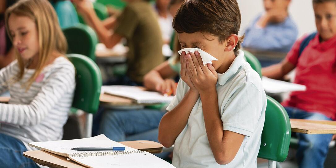 Sick boy at the school blowing his nose in class Sick boy at the school blowing his nose in class