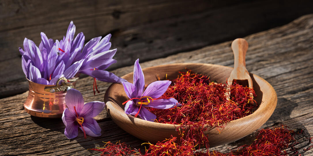 Saffron in wooden bowl on wooden table with saffron flowers on the side