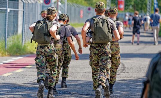 Rear view of Swiss Army soldiers walking at Swiss town.
