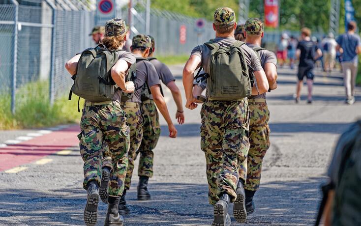 Rear view of Swiss Army soldiers walking at Swiss town.