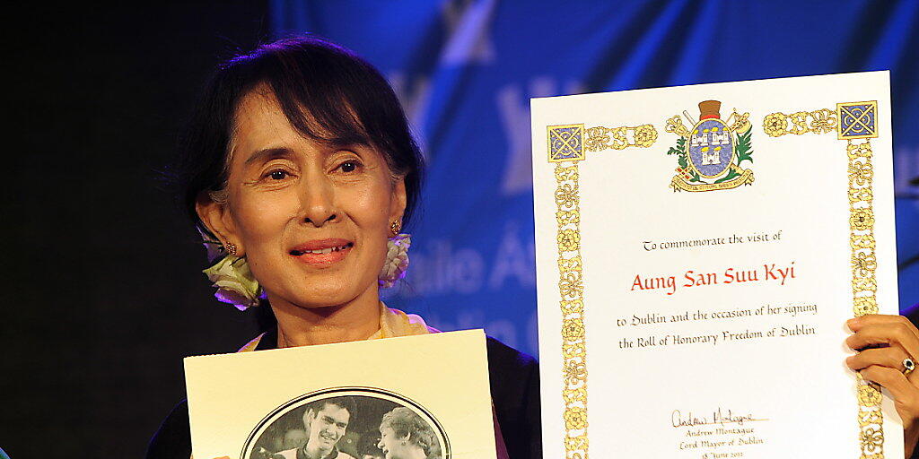 Aung San Suu Kyi mit der Urkunde der Menschenrechtsorganisation Amnesty International, die ihr 2009 den Ehrentitel "Botschafterin des Gewissens" verliehen hatte. Nun hat Amnesty Suu Kyi den Titel entzogen.  (Foto: KIM HAUGHTON/EPA)