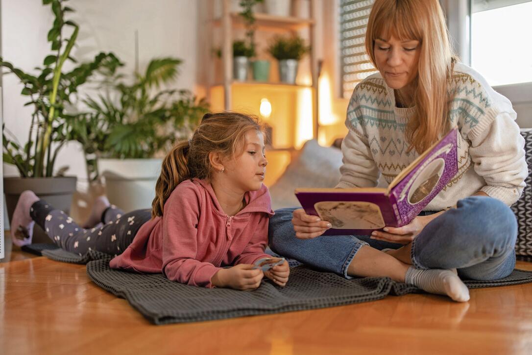 Mother and little daughter enjoying book together